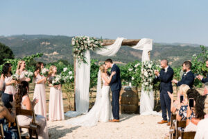 couple under a wedding arbor in a vineyard